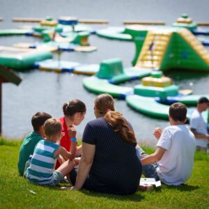 Folk sitter på gresset ved Hulfjell Vannpark