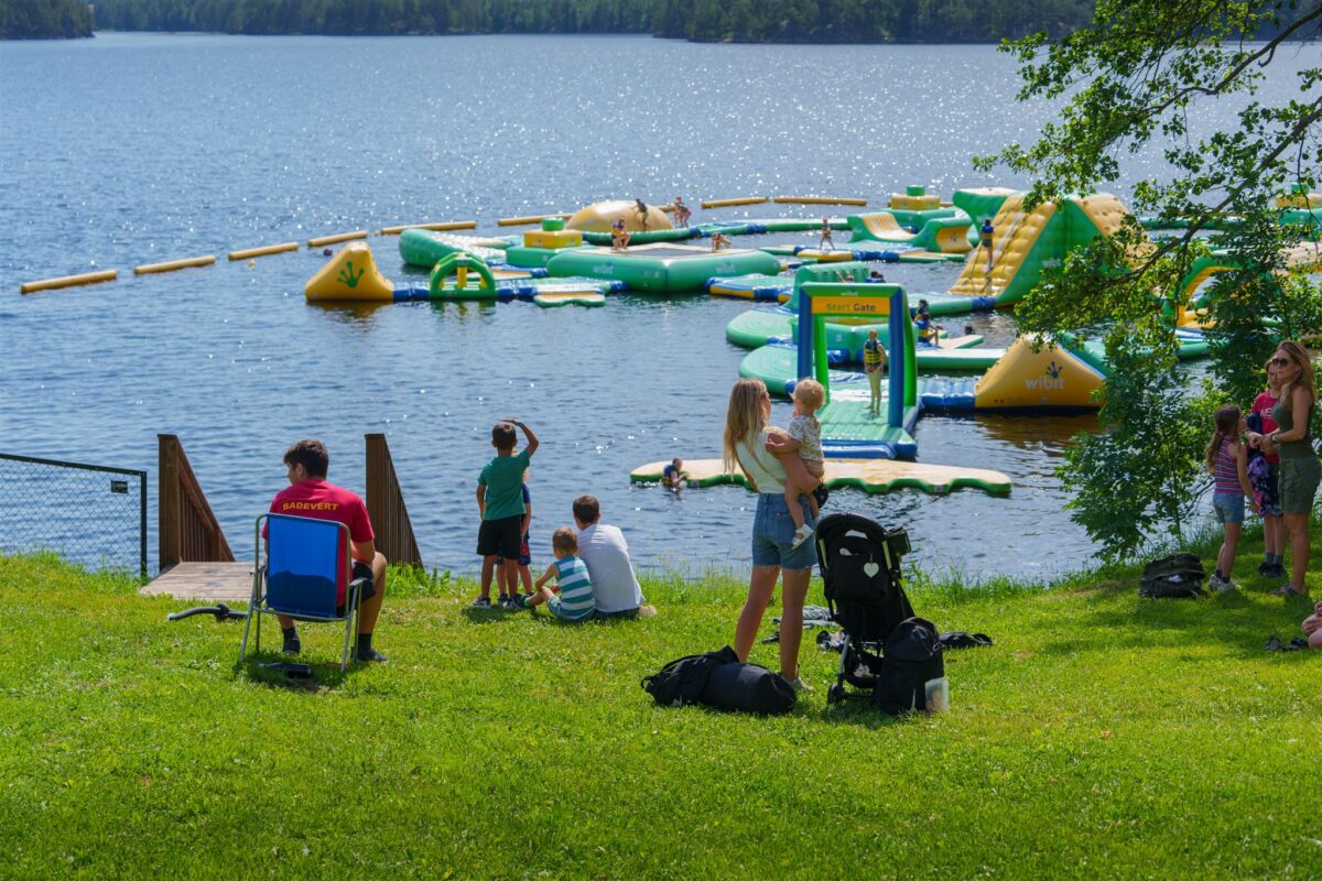 Folk som sitter og står i gresset og ser på Hulfjell Vannpark.